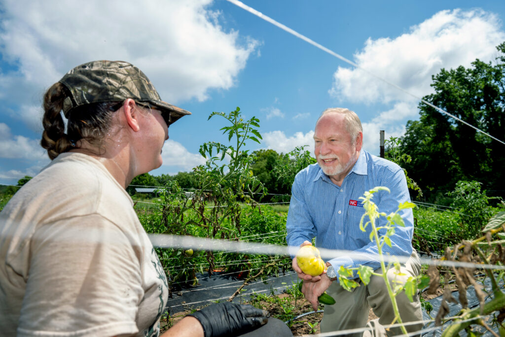 NC State Extension Director David Monks holds a freshly picked tomato while discussing crop production with Agroecology Education Farm Manager Sara Snyder at the university’s Lake Wheeler Road Field Lab in Raleigh, North Carolina.