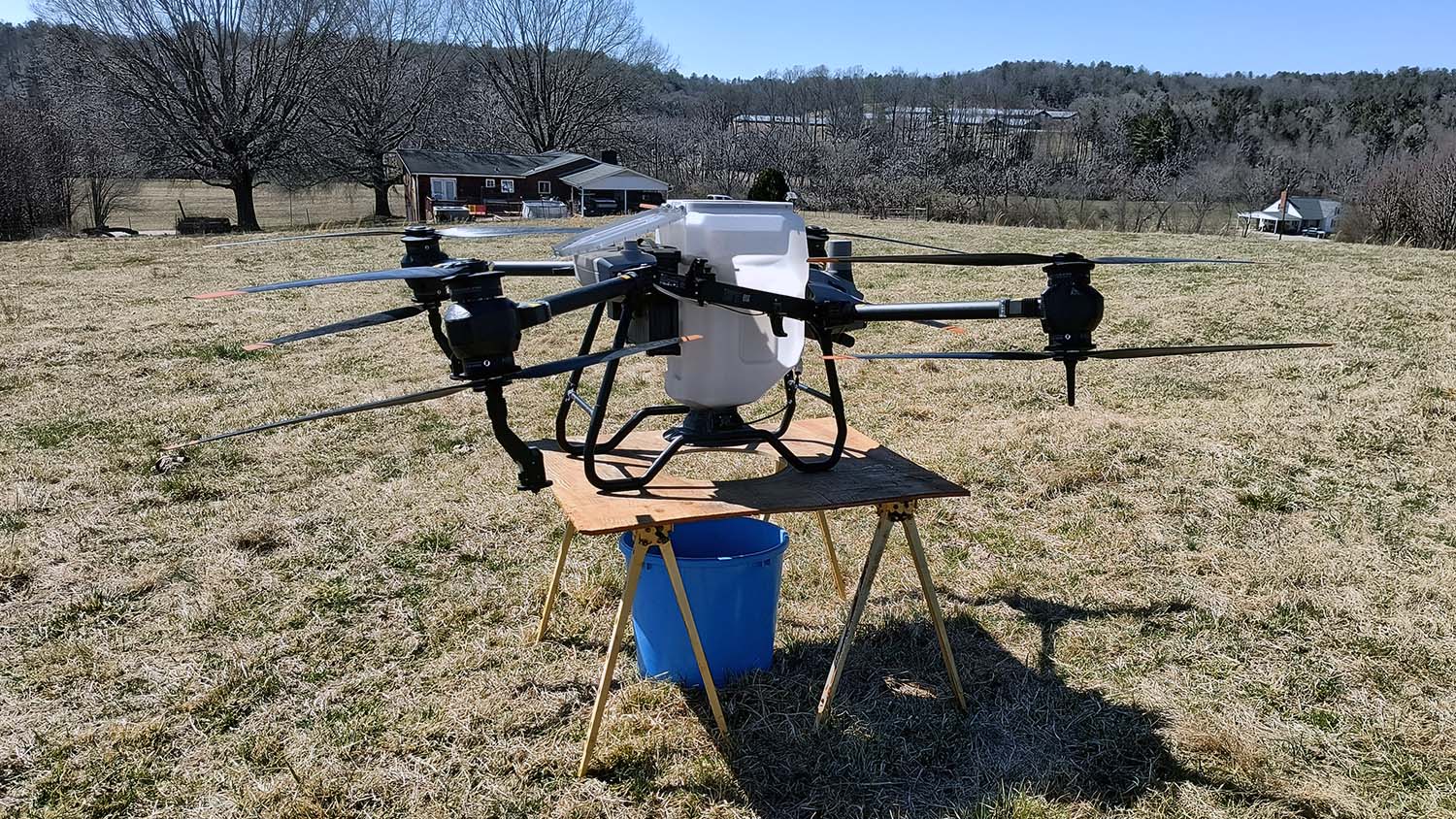 An agricultural drone rests on a platform while performing a seed calibration